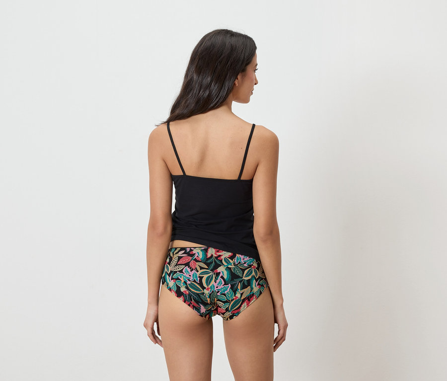 Femme vue de dos portant un débardeur noir et une culotte à motifs floraux.
