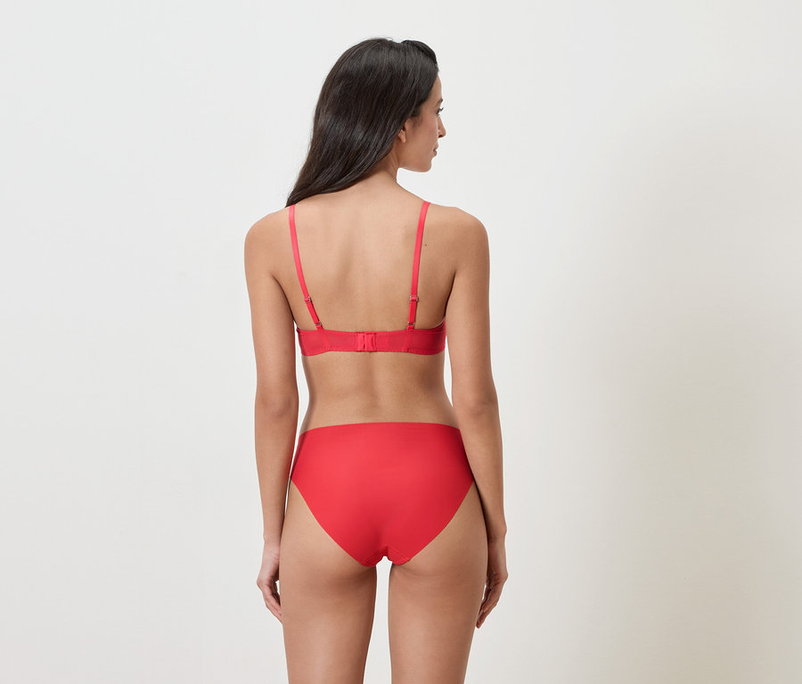 Femme vue de dos portant des sous-vêtements rouges sur un fond blanc.