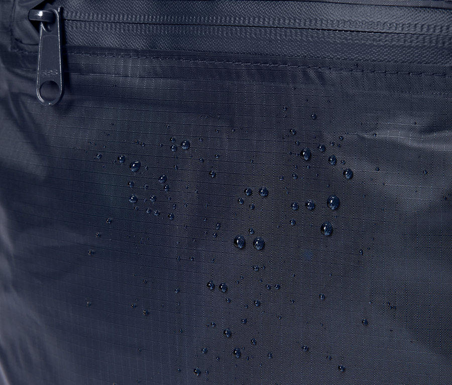 Gros plan d'un sac en tissu bleu marine avec fermeture éclair et gouttes d'eau.