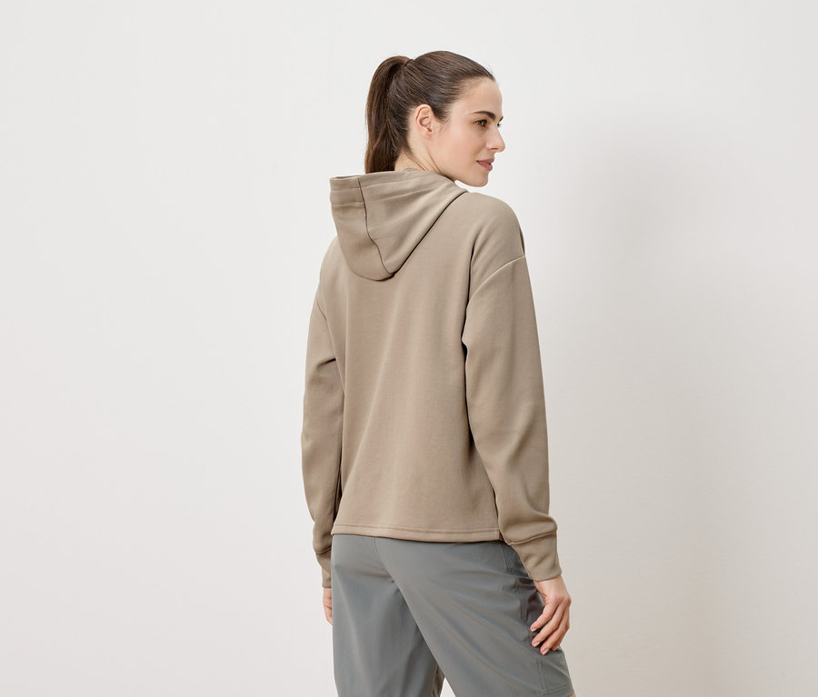 Femme vue de dos, portant un sweat à capuche beige et un short gris.