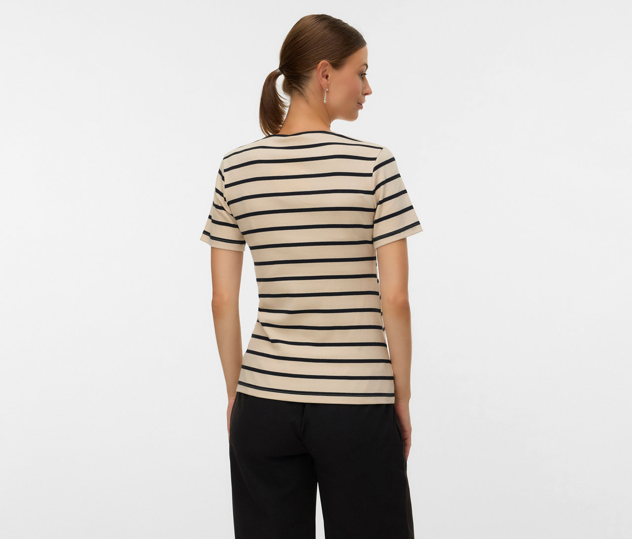 Femme vue de dos portant un t-shirt de grossesse MAMALICIOUS «
MLLANE TESS » beige à rayures noires et un pantalon noir.