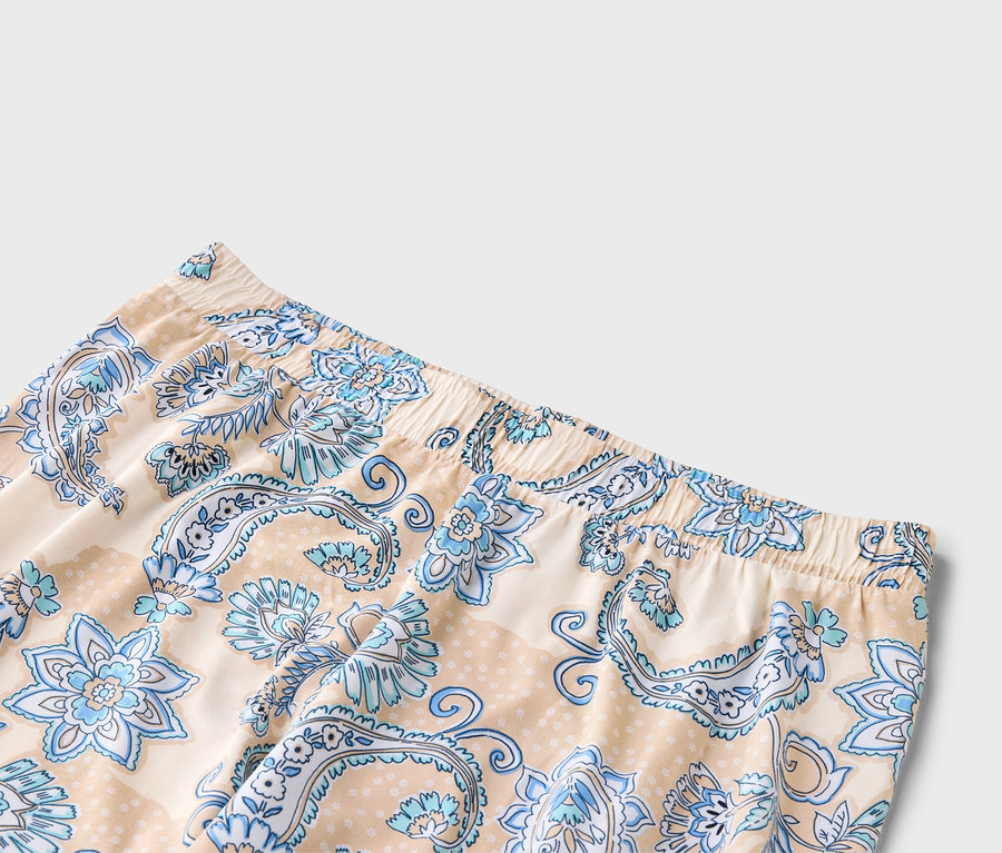 Gros plan d'un pantalon beige avec un motif floral bleu et une taille élastique.