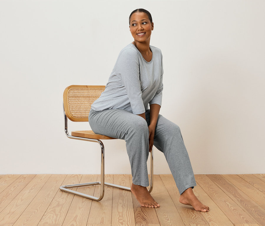Femme assise sur une chaise portant un pyjama gris rayé.