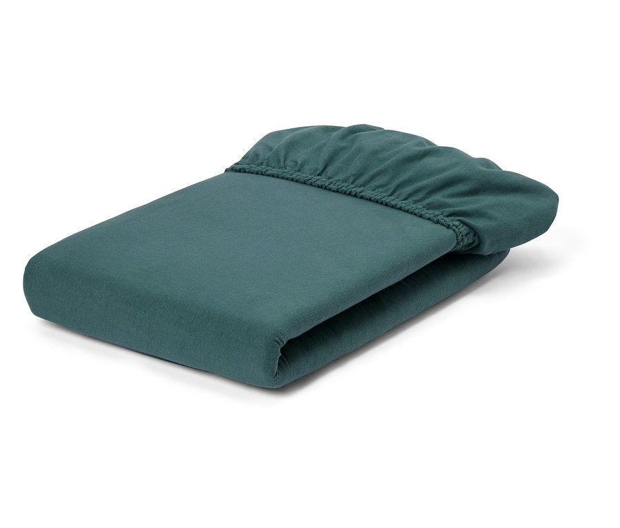 Un drap-housse plié, couleur pétrole, repose sur un fond blanc.