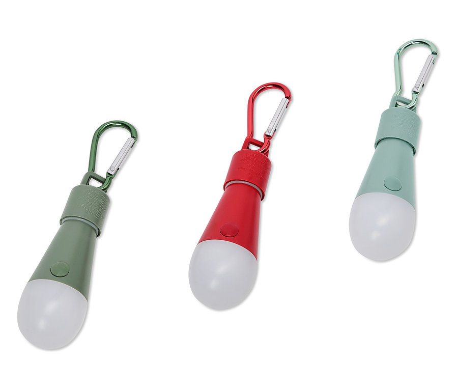 Trois lampes LED colorées avec mousquetons reposent sur un fond blanc.