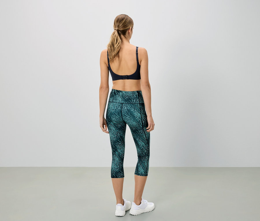 Femme vue de dos, portant un soutien-gorge de sport et un legging capri vert à motifs.