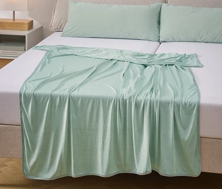 Un drap-housse et deux oreillers vert menthe sont posés sur un lit avec des draps blancs.