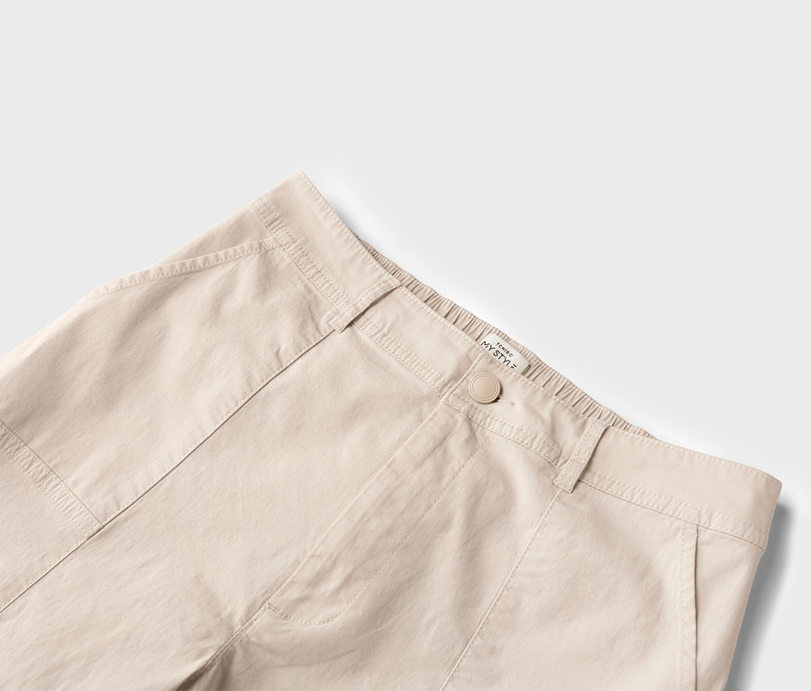 Gros plan d'un pantalon beige avec bouton et poches.