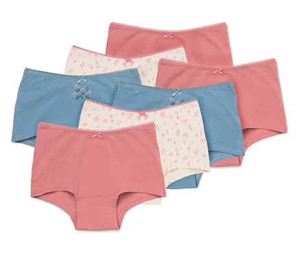 Sept culottes pour filles de différentes couleurs et motifs, y compris rose uni, bleu clair uni et crème à imprimé floral. Chaque culotte a un petit nœud à l'avant.