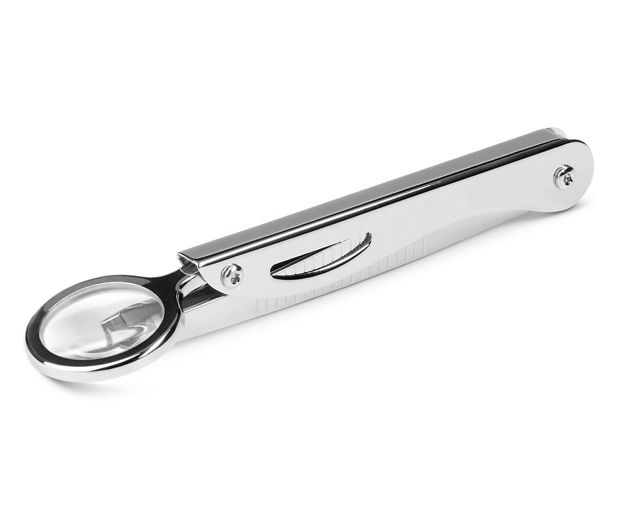 Une loupe pliante argentée est posée sur un fond blanc.