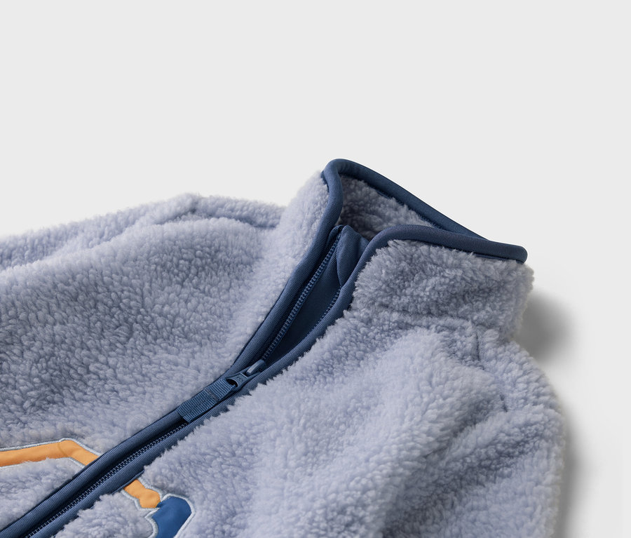 Gros plan sur une veste en polaire bleu clair avec une fermeture éclair bleue.