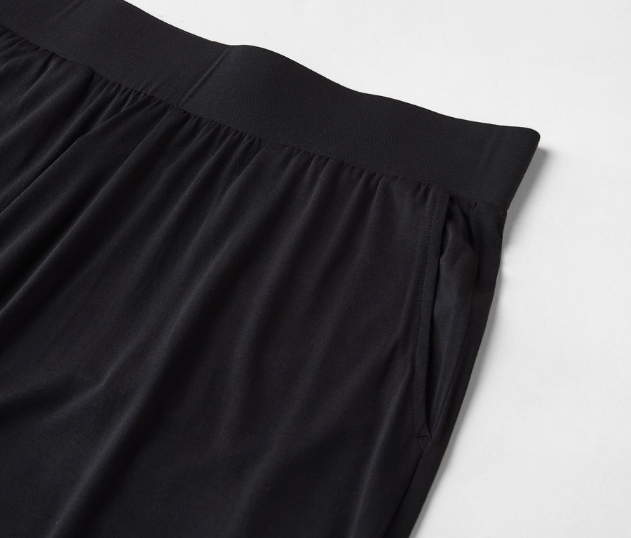 Gros plan d'un pantalon noir avec une taille élastique et une poche sur le côté.