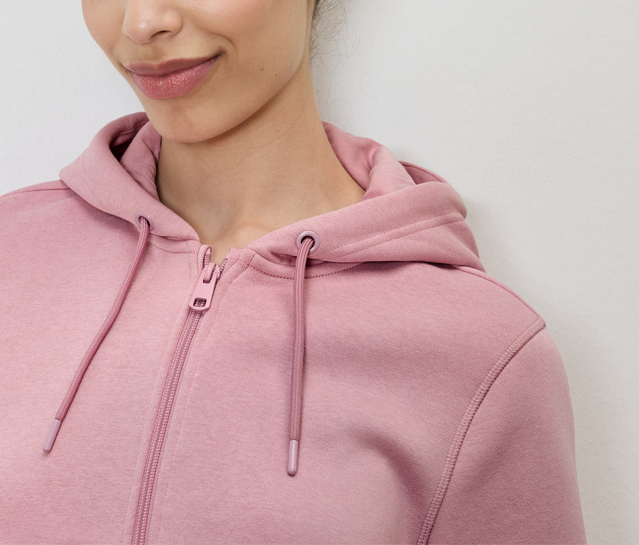 Gros plan d'une femme portant un sweat à capuche rose zippé.