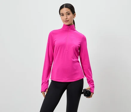 Une femme portant un haut rose à manches longues avec fermeture éclair et un legging noir tient une bouteille d'eau sur fond blanc.