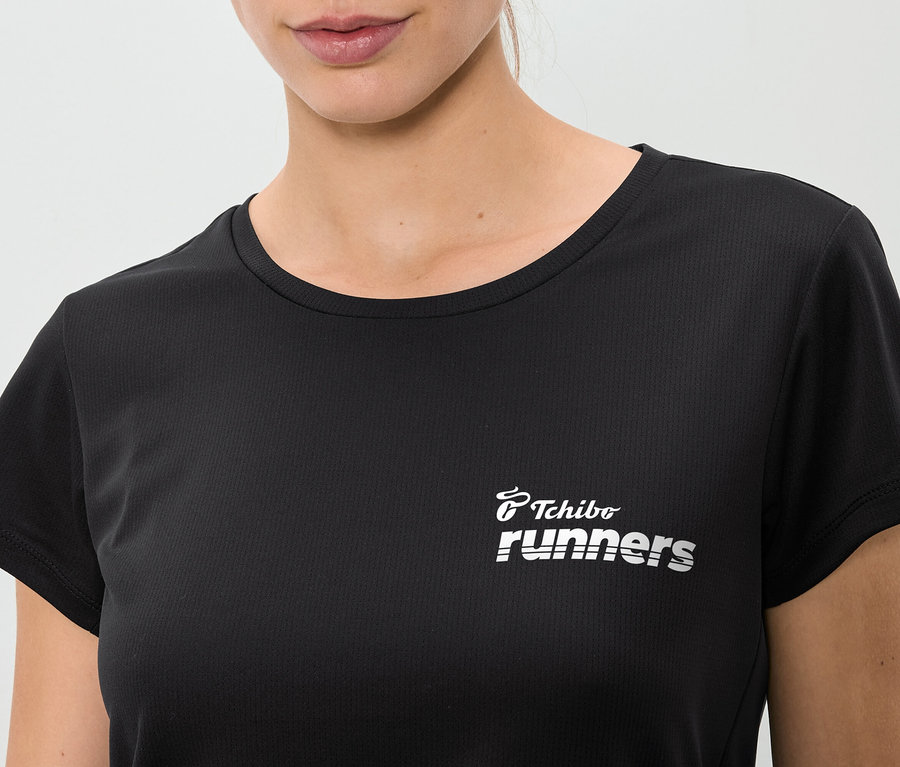 Gros plan d'une femme portant un t-shirt noir avec l'inscription "Tchibo runners".