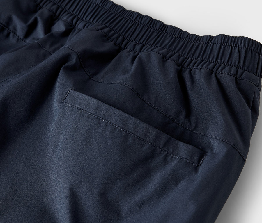 Gros plan d'un pantalon de survêtement bleu marine avec une taille élastique et une poche arrière.
