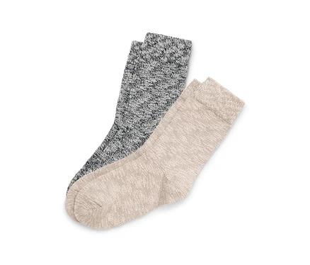 Deux chaussettes tricotées mouchetées, une gris foncé et une beige clair, sont posées en diagonale sur un fond blanc.