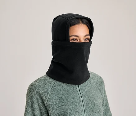 Une personne porte une cagoule noire et une veste polaire verte. Seuls les yeux sont visibles.