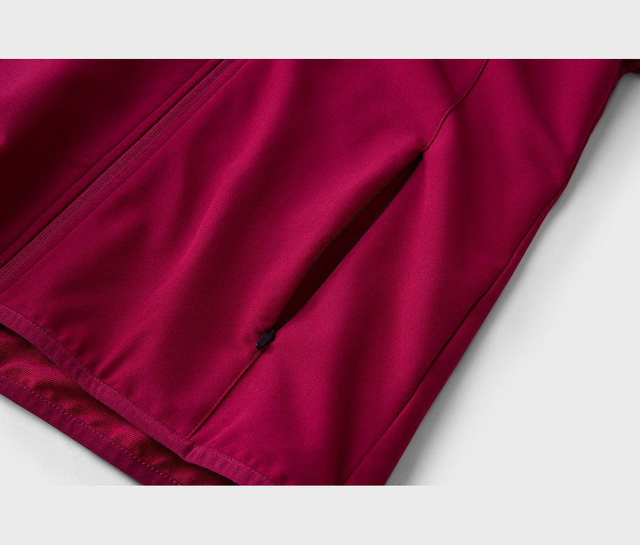 Gros plan d'une veste rouge foncé avec une fermeture éclair diagonale sur le côté gauche et une poche diagonale zippée sur le côté droit.