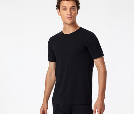 Homme portant un t-shirt SCHIESSER noir et un boxer noir, debout devant un fond blanc.