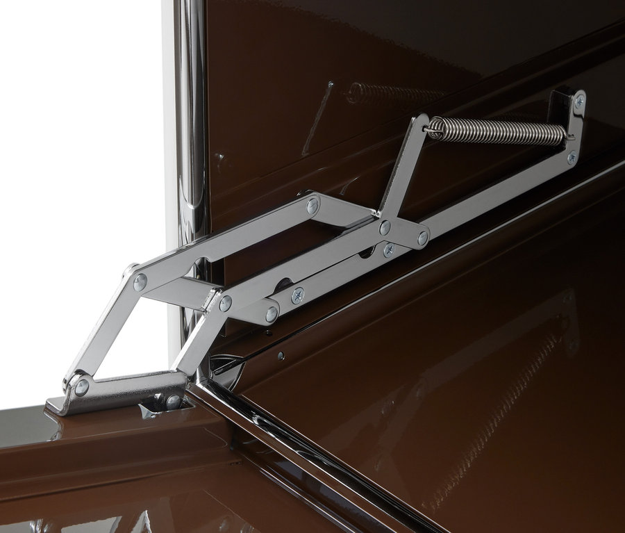 Mécanisme de charnière chromé multi-articulé avec ressort, fixé sur une surface marron brillante.