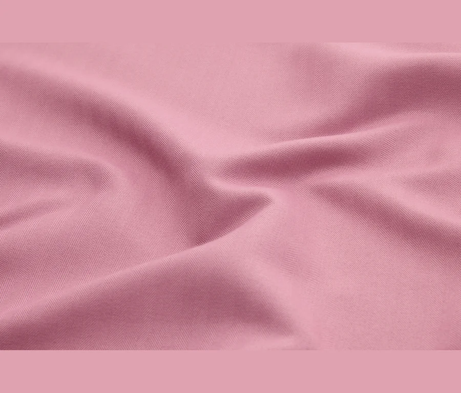 Tissu rose avec un motif à chevrons subtil et des plis doux.