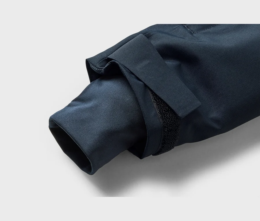 Gros plan d'une manche de veste bleu foncé avec une manchette ajustable à scratch.