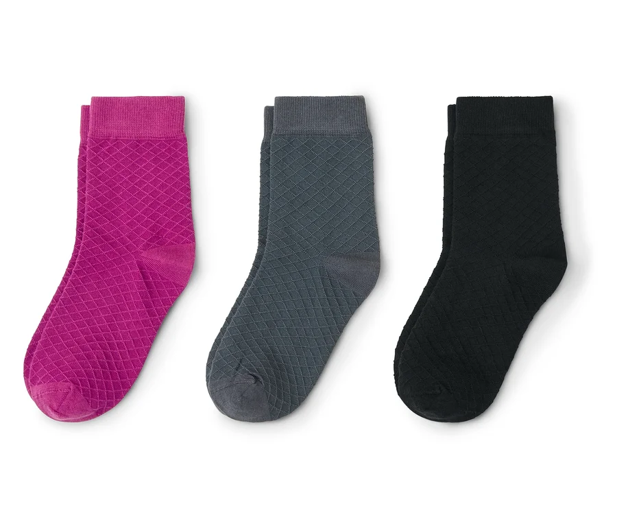 Trois chaussettes à motif losanges, de gauche à droite : une magenta, une gris foncé et une noire.