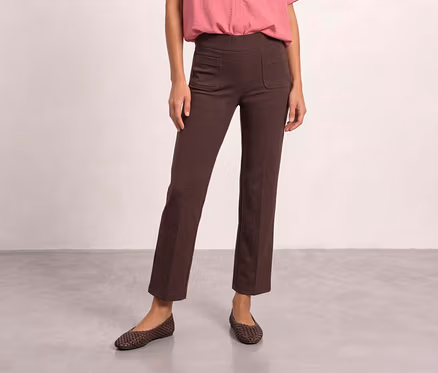 Une personne porte un pantalon en tissu Street One marron avec des poches avant, une chemise rose et des ballerines tressées marron.