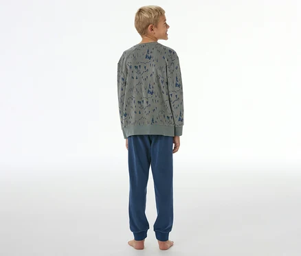 Jeune garçon de dos portant un pyjama pour enfant SCHIESSER gris à motif d'arbres bleus et pantalon bleu à bords-côtes.