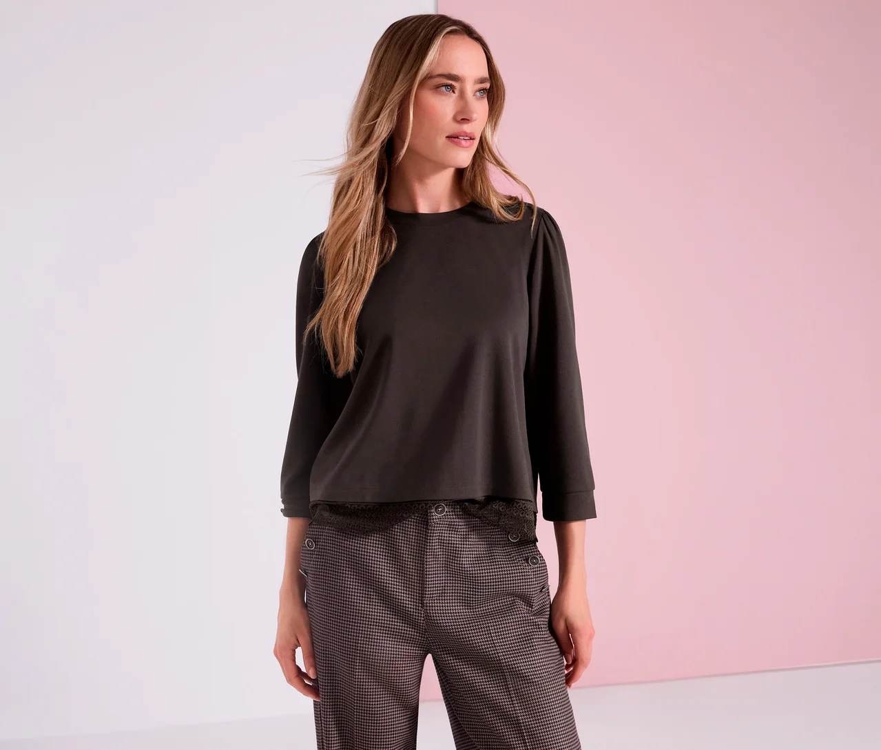 Une femme porte un T-shirt en jersey 3/4 Street One marron à manches bouffantes et un pantalon à motifs devant un fond rose et blanc.