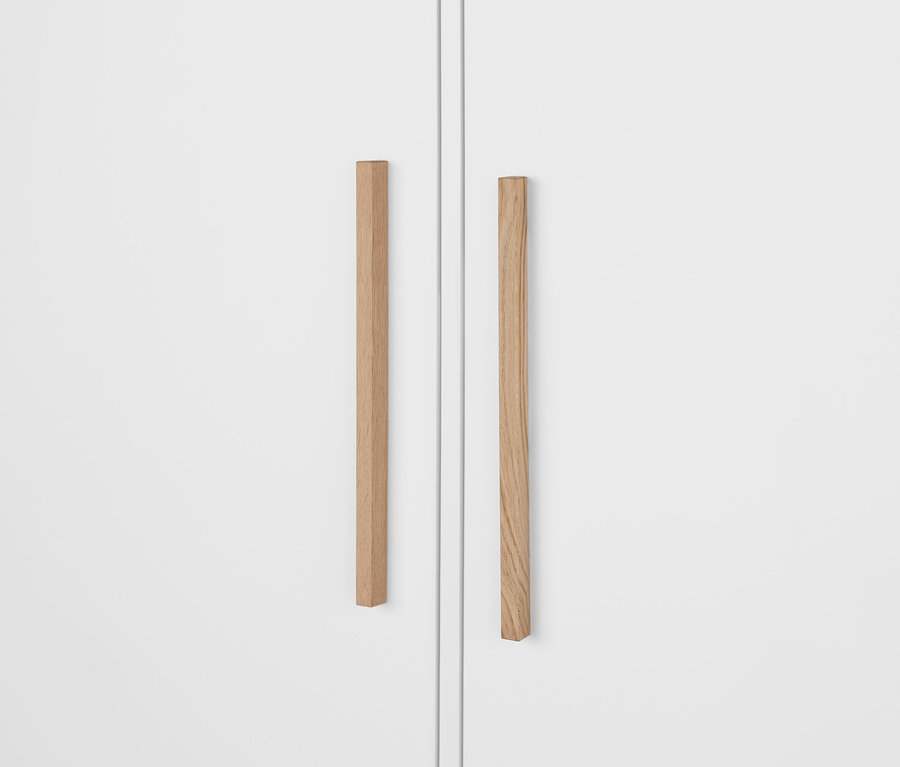 Gros plan sur une armoire de chambre « Eklund » blanche avec tiroirs, montrant des poignées en bois.
