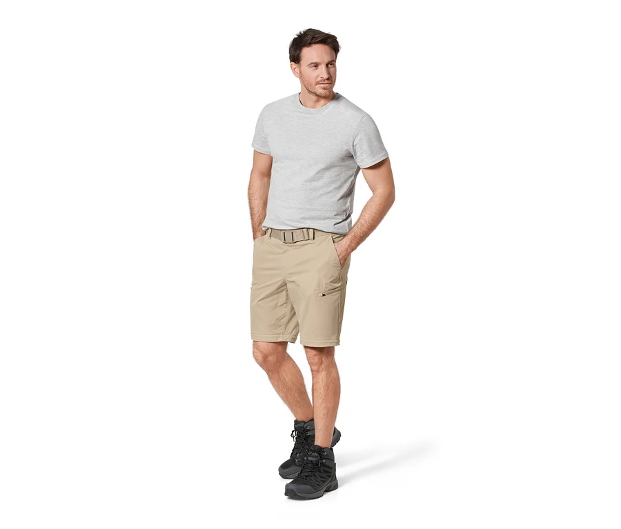 Un homme debout, les mains dans les poches d'un pantalon fonctionnel beige 2 en 1.