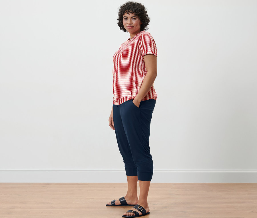 Femme portant un T-shirt à rayures et un pantalon 3/4 en jersey, debout de profil.