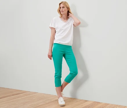 Femme posant dans un pantalon stretch 7/8 turquoise et un t-shirt blanc.