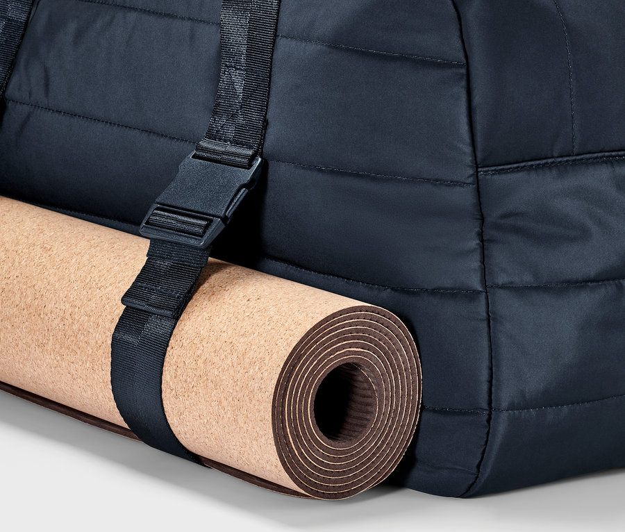 Partie d'un sac de sport avec un tapis de yoga fixé par une sangle.
