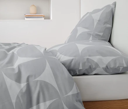 Gros plan d'une parure de lit en renforcé grise à motifs sur un lit.