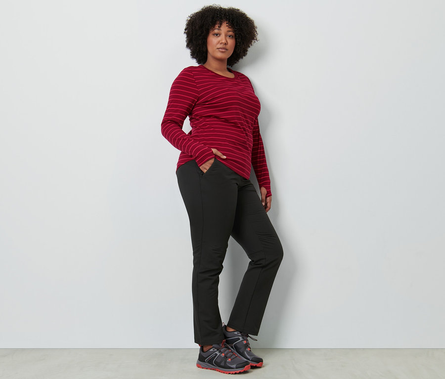 Femme posant en pantalon softshell et t-shirt de sport manches longues.