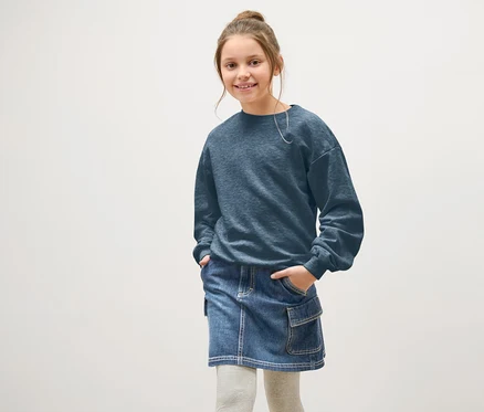 Fille souriante posant en jupe en jean bleue.