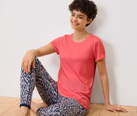 Femme assise par terre portant un t-shirt long rose vif.