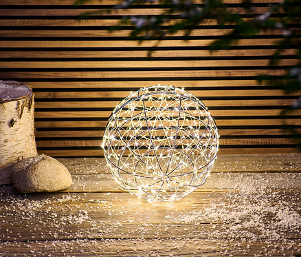 Une petite boule LED lumineuse est posée sur une table en bois à côté d'un morceau de bois.