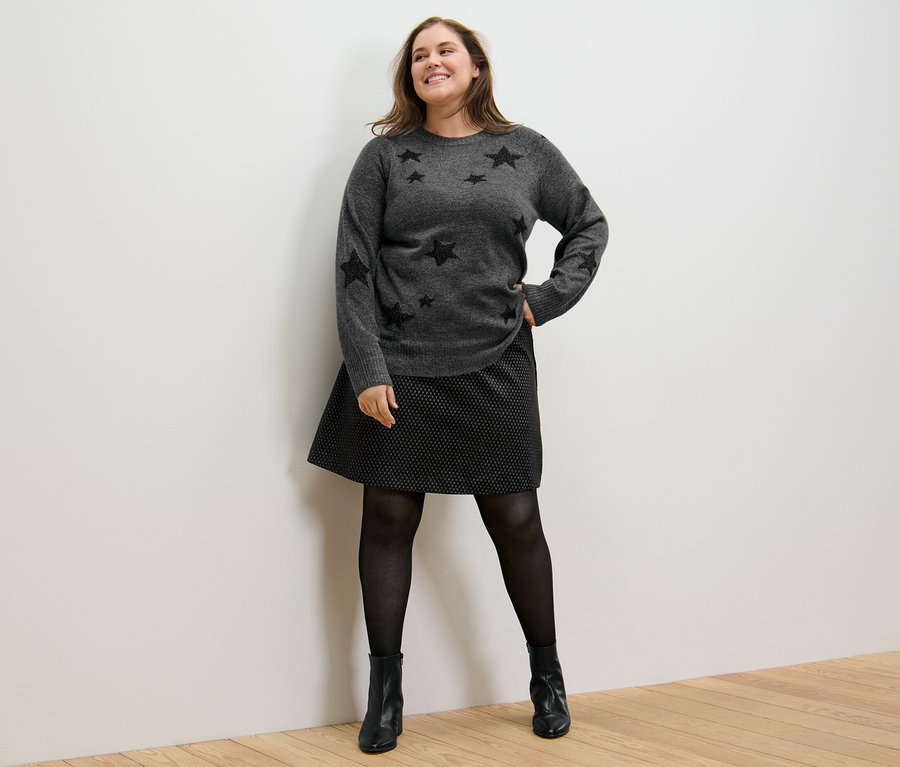 Femme posant en pull en maille et jupe en jacquard scintillante.