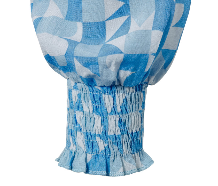 Détail d'une blouse imprimée avec un motif géométrique bleu et blanc et une finition élastique.