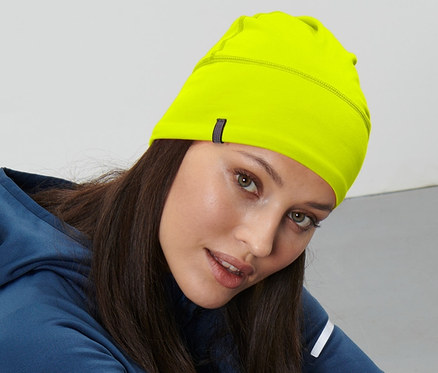 Une femme est assise par terre et porte un bonnet thermique jaune néon.