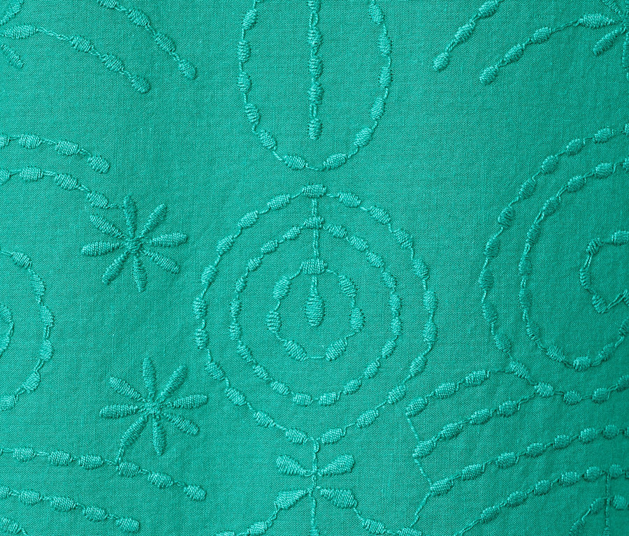 Détail d'un chemisier vert avec broderie.