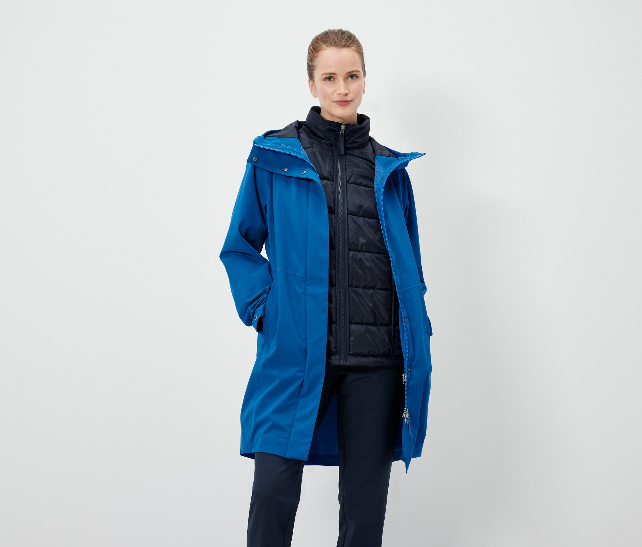 Une femme porte un manteau bleu et une veste noire.