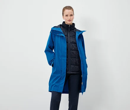 Une femme porte un manteau bleu et une veste noire.