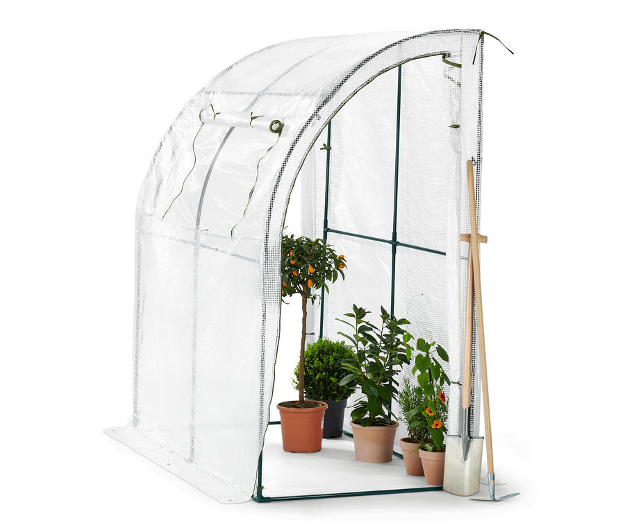 À l'intérieur de la serre inclinée pour protéger les plantes, il y a quatre plantes en pot et une pelle.