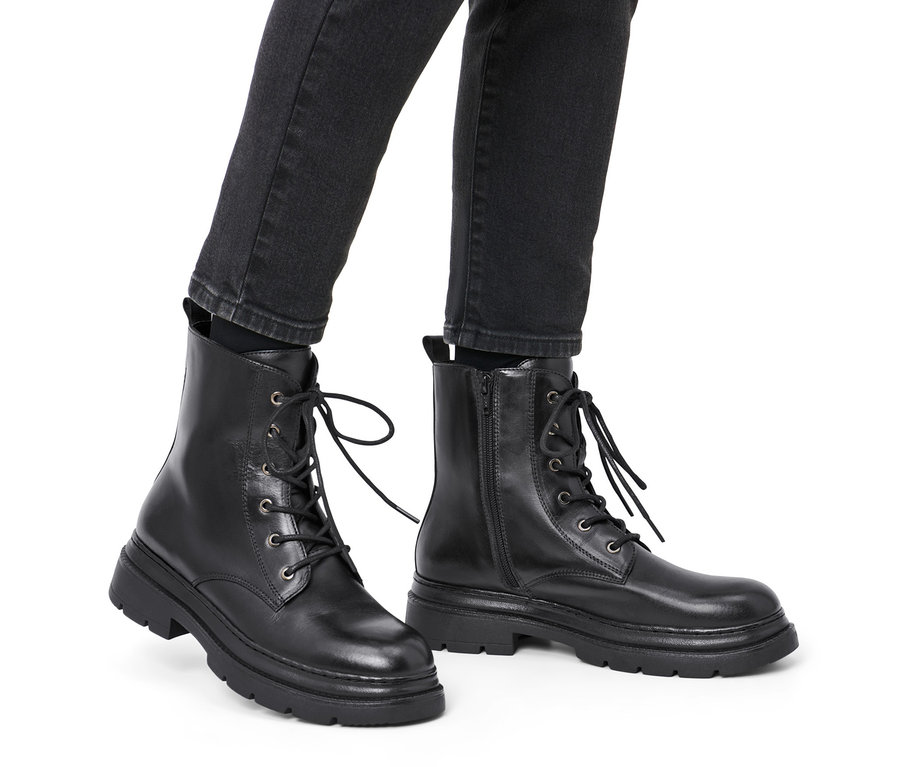 Jambes portant des bottines en cuir noires.