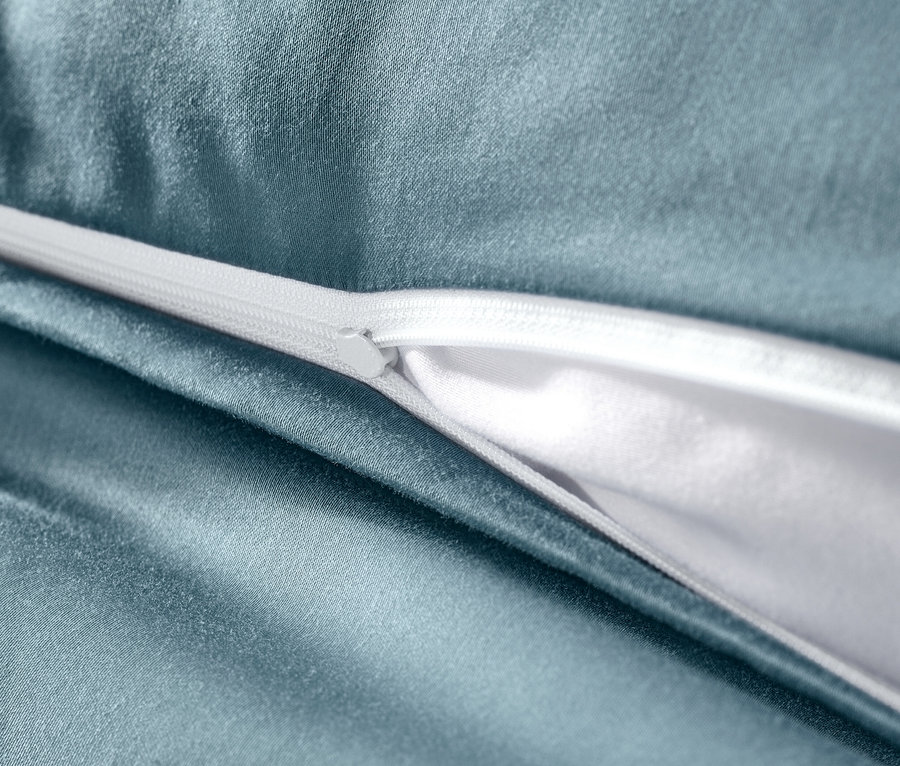 Gros plan d'une parure de lit bleu en satin de coton avec fermeture éclair blanche.